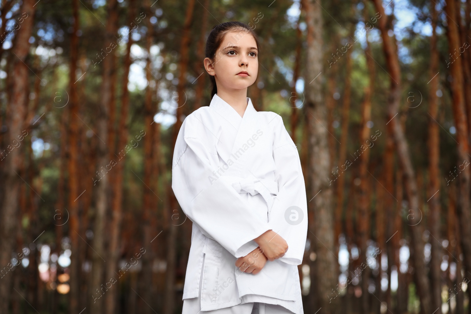 Photo of Cute little girl in kimono in forest. Karate practicing