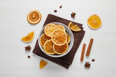 Photo of Many dry orange slices and spices on white wooden table, flat lay
