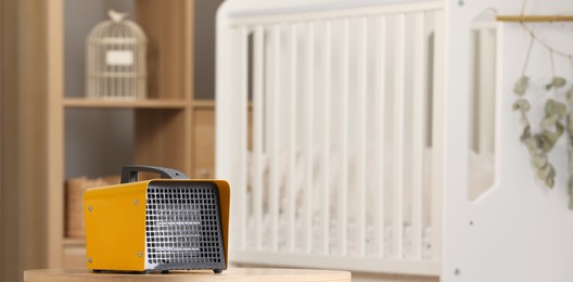 Photo of Modern electric fan heater on coffee table in cozy room
