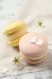 Photo of Delicious colorful macarons and flowers on white marble table