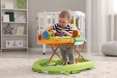 Photo of Cute baby making first steps with toy walker at home