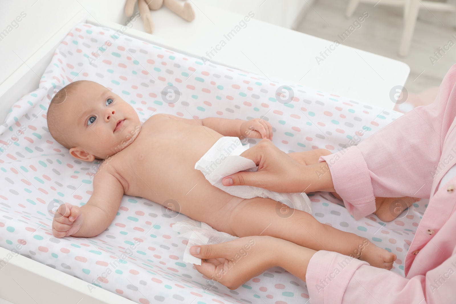 Photo of Mother changing her baby's diaper on table at home