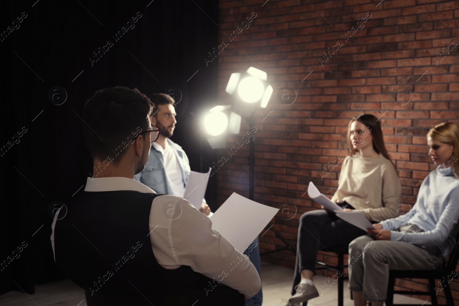 Photo of Professional actors reading their scripts during rehearsal in theatre