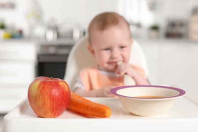 Photo of Adorable little child having breakfast in highchair indoors. Healthy baby food