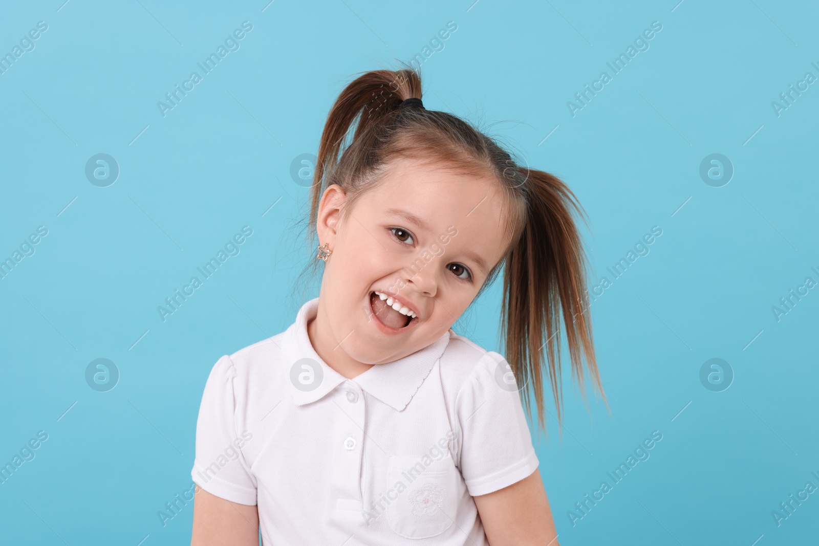 Photo of Portrait of happy little girl on light blue background