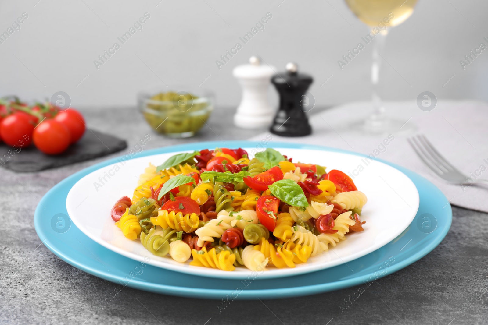 Photo of Colorful pasta with basil and tomatoes on grey table