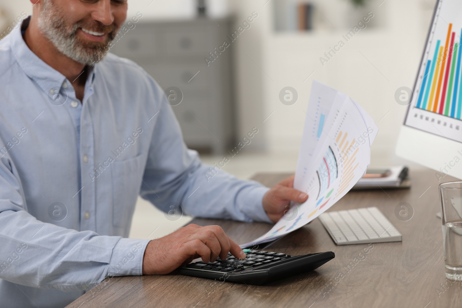 Photo of Professional accountant using calculator at wooden desk in office, closeup