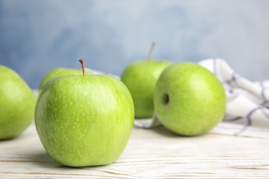 Fresh ripe green apples on white wooden table against blue background, closeup view. Space for text