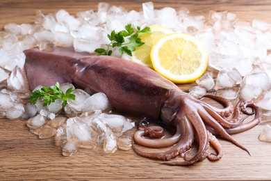Fresh raw squid with ice, lemon and parsley on wooden table