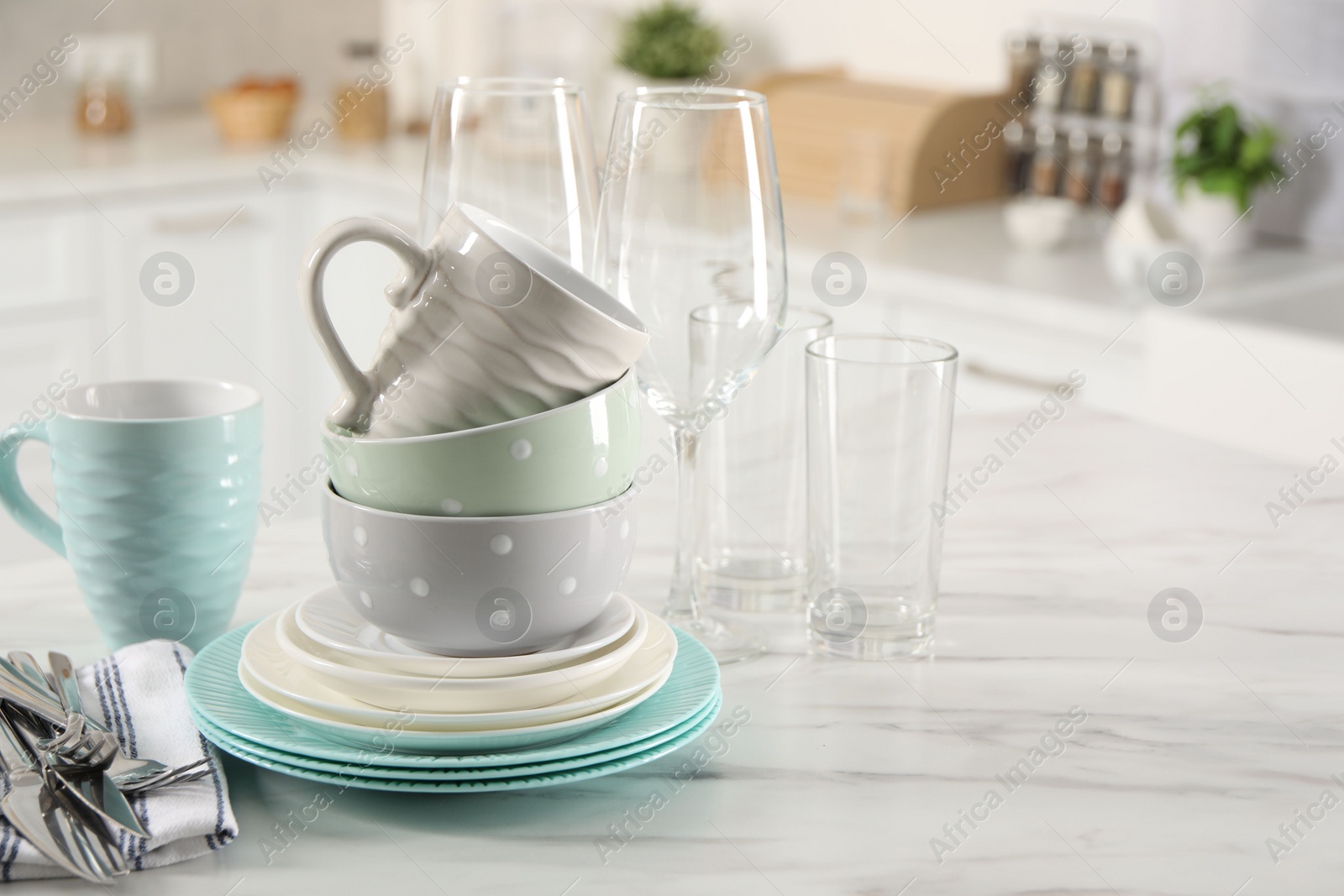 Photo of Many different clean dishware, cutlery, glasses and cups on white marble table in kitchen. Space for text