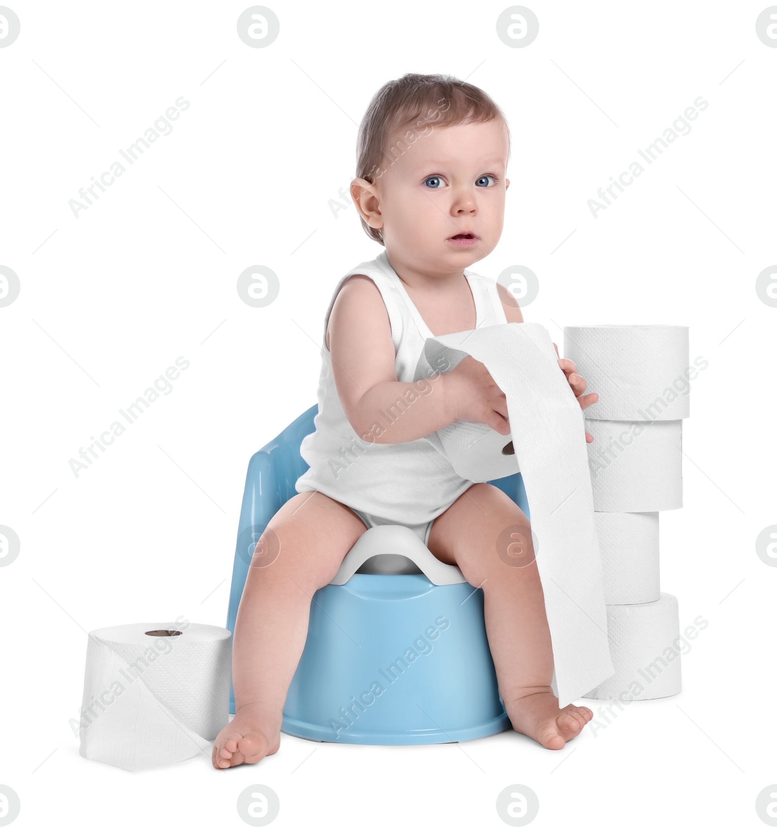 Photo of Little child sitting on baby potty and stack of toilet paper rolls against white background