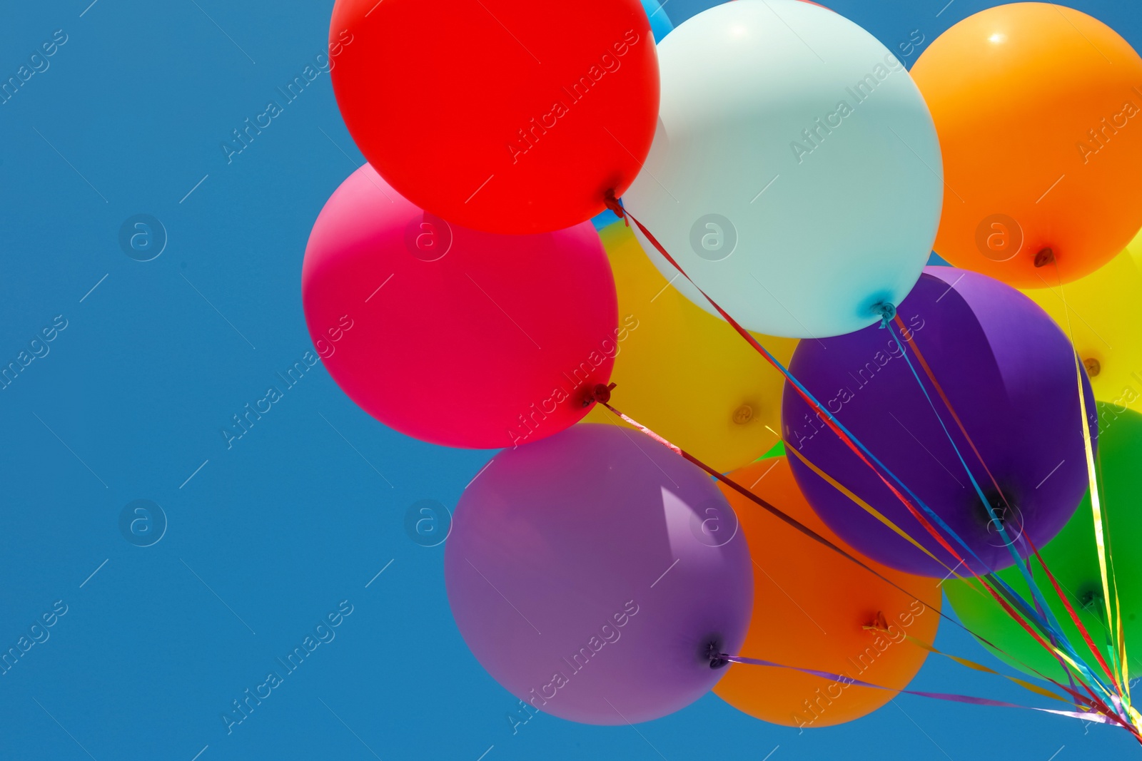 Photo of Bunch of colorful balloons against blue sky, low angle view