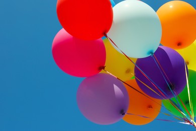 Photo of Bunch of colorful balloons against blue sky, low angle view