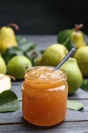 Photo of Delicious pear jam and fresh fruits on grey wooden table. Space for text