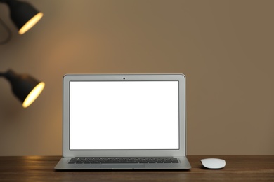 Laptop with blank screen on table indoors. Space for text