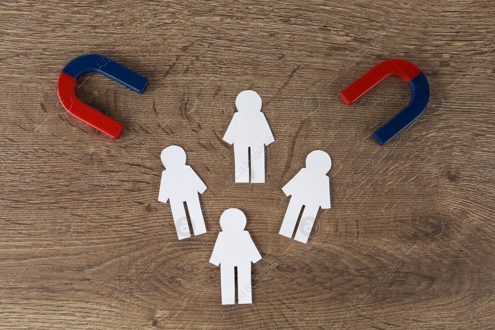 Photo of Magnet and paper people on wooden table, flat lay