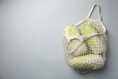 Photo of Fresh Chinese cabbages in string bag on light background, top view. Space for text