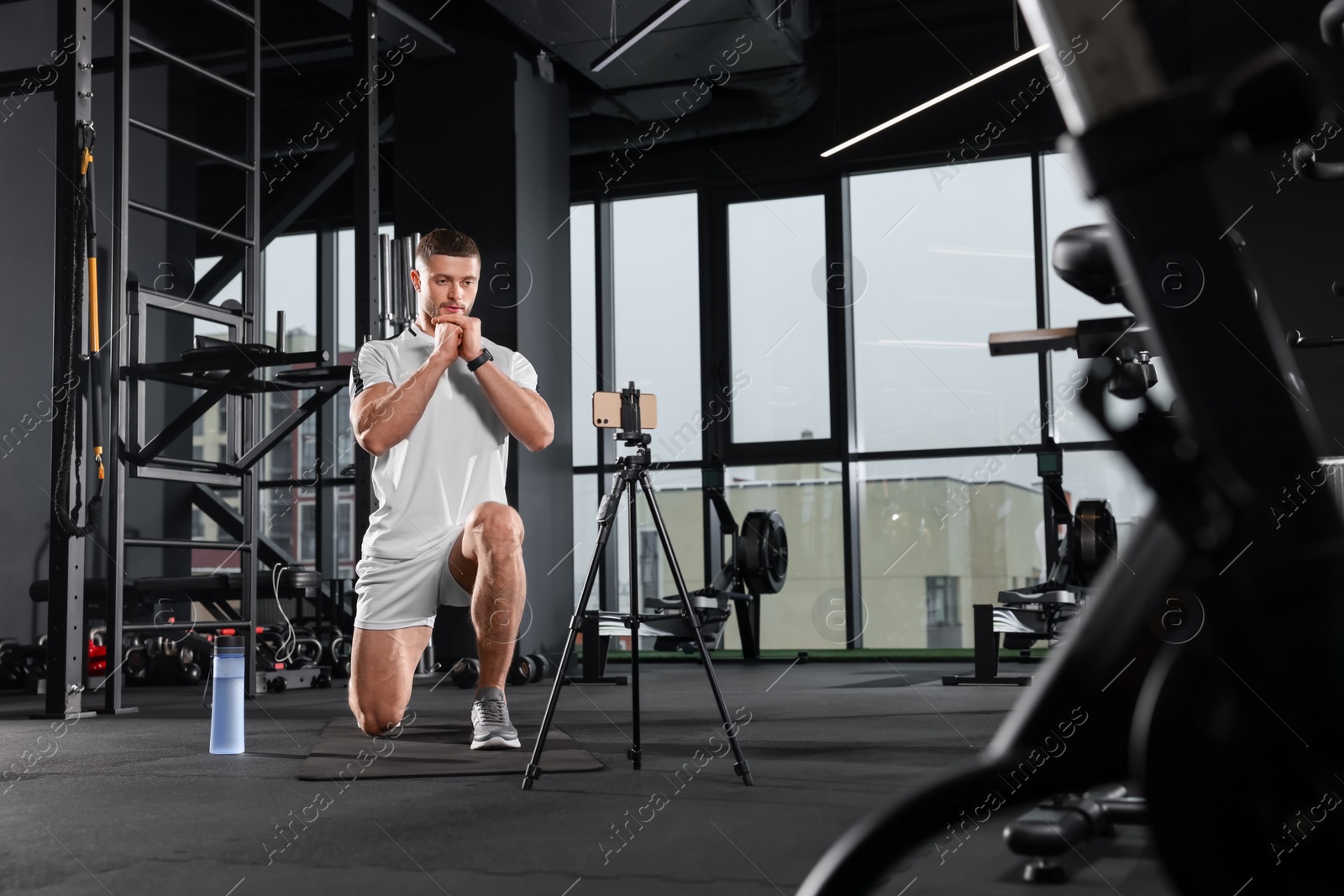 Photo of Trainer streaming online workout with phone at gym