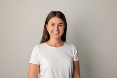 Photo of Smiling young woman in white t-shirt on light background