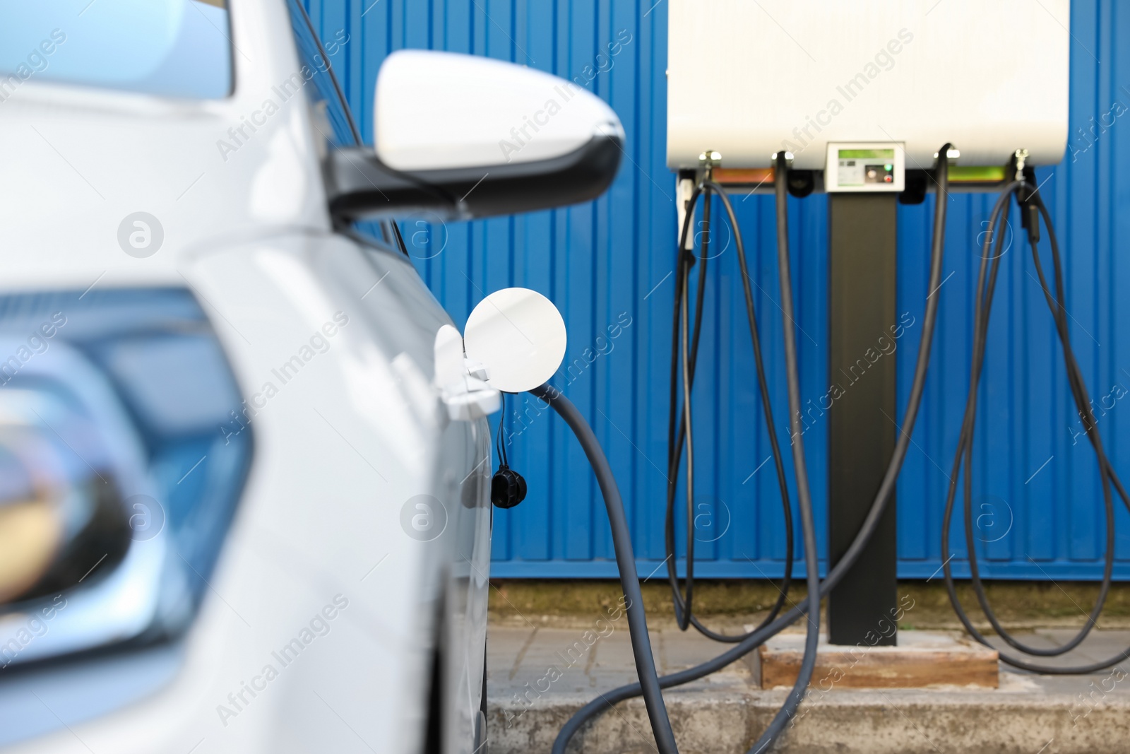 Photo of Charging modern electric car from station outdoors