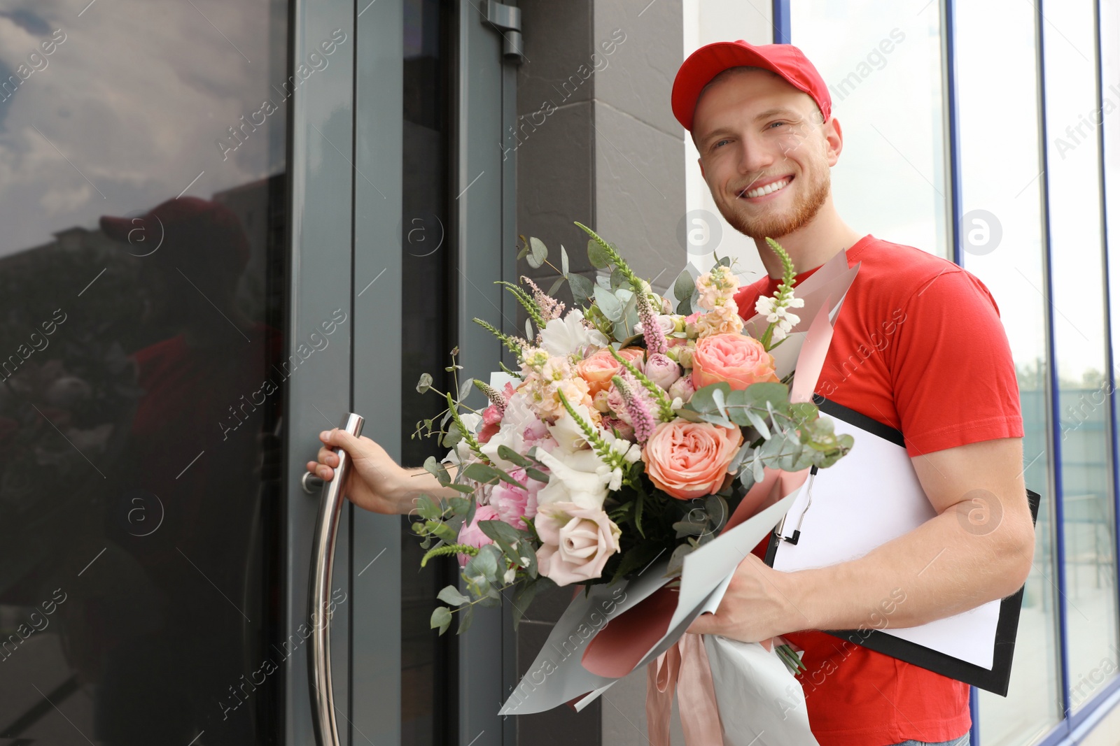 Photo of Delivery man with beautiful flower bouquet near front door