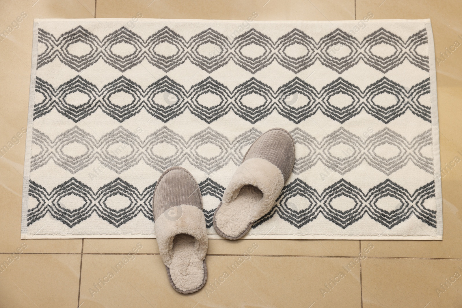 Photo of Soft bath mat and slippers on floor, top view