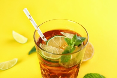 Photo of Glass of refreshing iced tea on yellow background