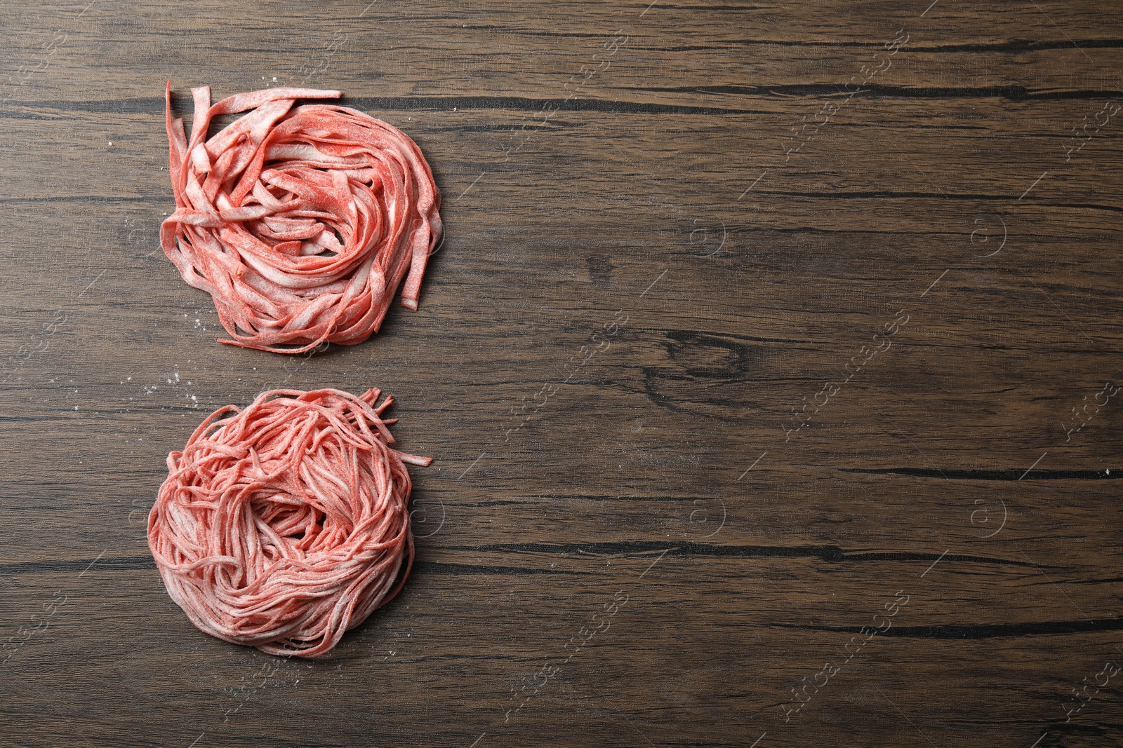 Photo of Rolled pasta painted with food colorings on wooden table, flat lay. Space for text