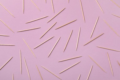 Wooden toothpicks on pink background, flat lay