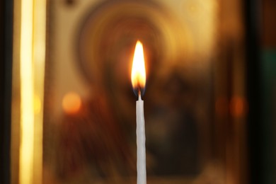 Photo of One burning candle in church, closeup view