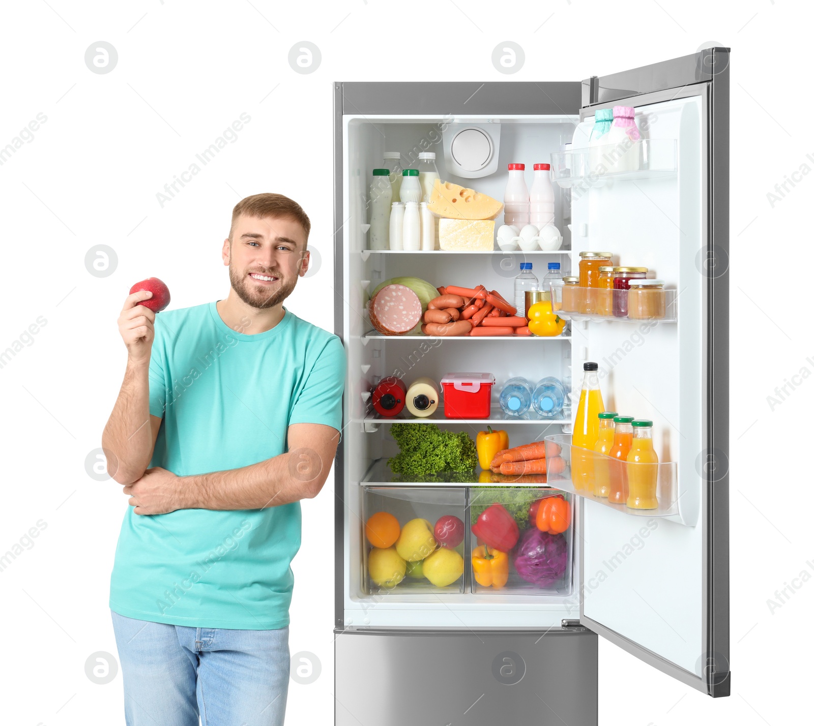 Photo of Young man with apple near open refrigerator on white background