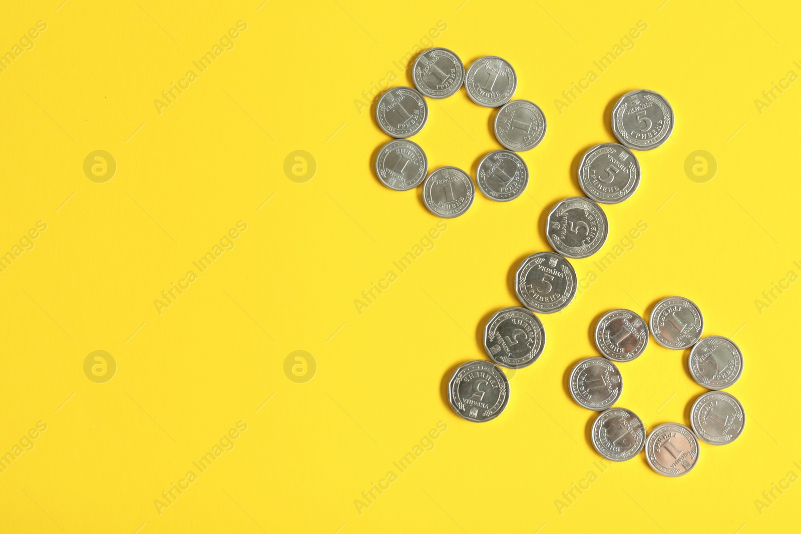 Photo of Percent sign made of Ukrainian hryvnia coins on yellow background, flat lay. Space for text