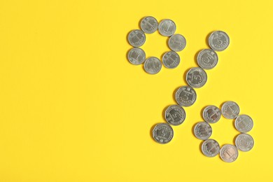 Photo of Percent sign made of Ukrainian hryvnia coins on yellow background, flat lay. Space for text