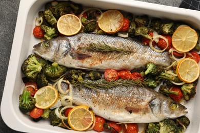 Photo of Delicious fish with vegetables and lemon in baking dish on grey table, top view