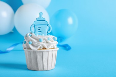 Beautifully decorated baby shower cupcake with cream and boy topper on light blue background. Space for text