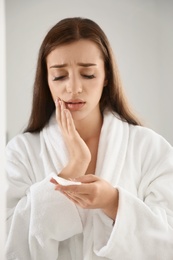 Young woman holding cotton pad with fallen eyelashes indoors