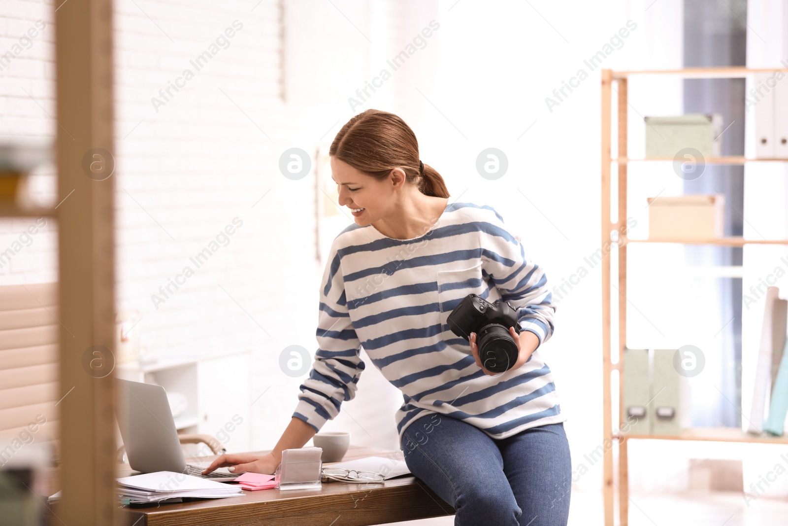 Photo of Young journalist working with laptop in light office