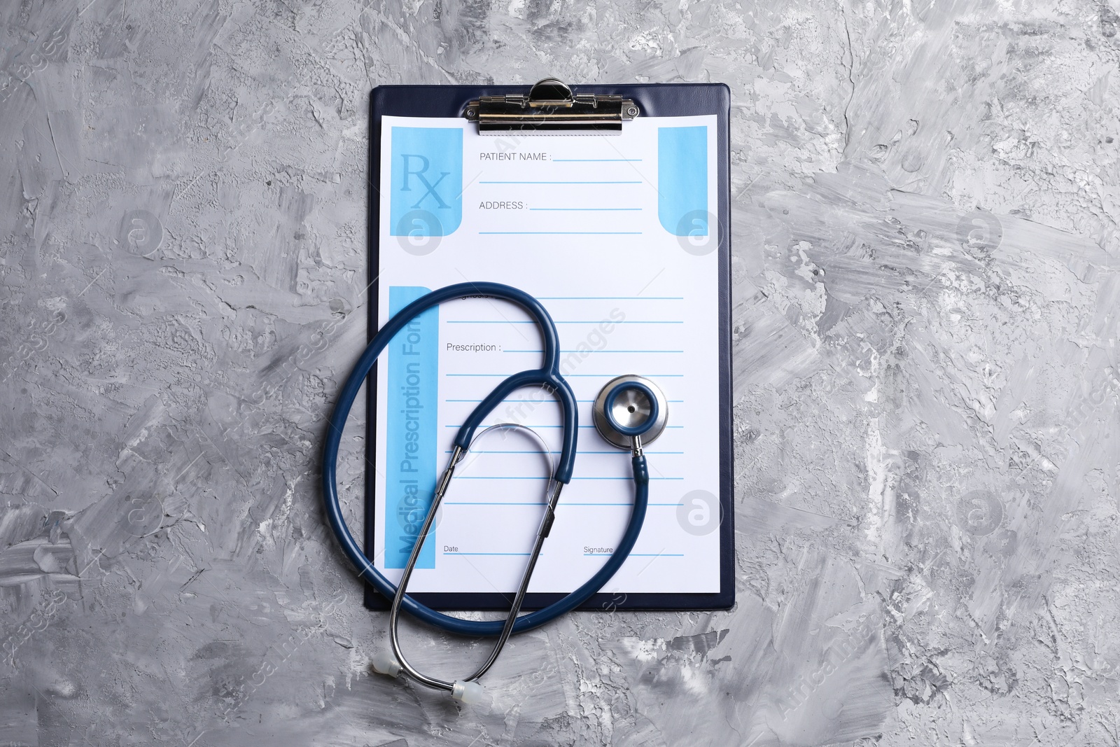 Photo of Medical prescription form with empty fields and stethoscope on grey textured table, top view