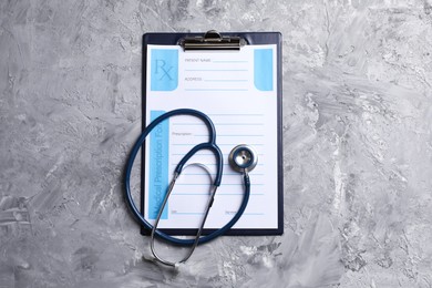Medical prescription form with empty fields and stethoscope on grey textured table, top view