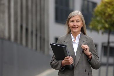 Photo of Beautiful woman with folders outdoors, space for text. Lawyer, businesswoman, accountant or manager