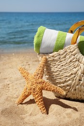Photo of Bag with beach accessories on sand near sea