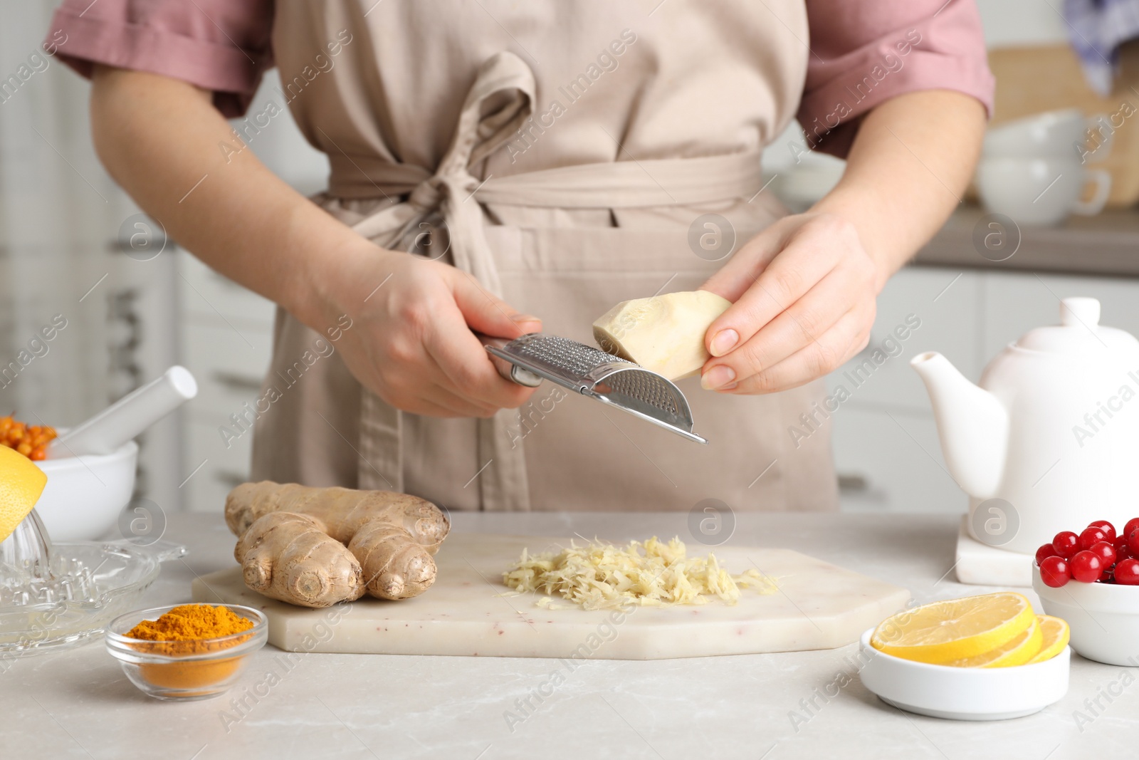 Photo of Woman making immunity boosting drink with grated ginger at marble table, closeup