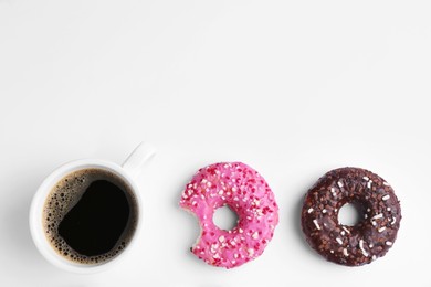 Tasty donuts and cup of coffee on white background, flat lay. Space for text