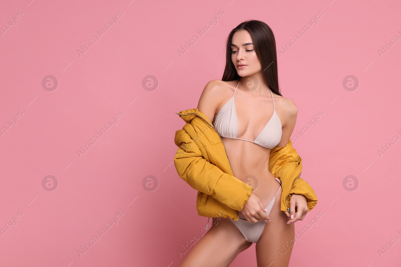 Photo of Young woman in stylish bikini and jacket on pink background, space for text