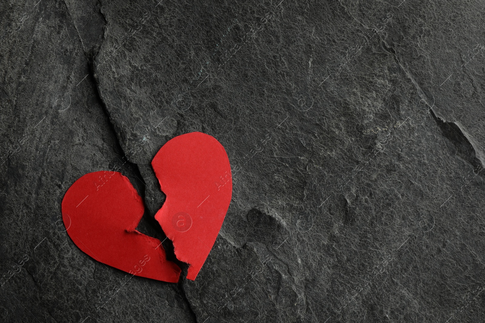 Photo of Broken heart. Halves of torn red paper heart on dark grey table, top view. Space for text