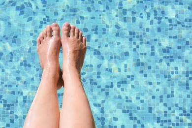Photo of Woman holding feet over water in swimming pool, closeup. Space for text