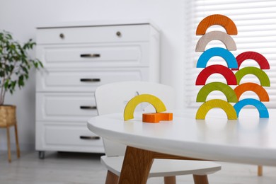 Colorful wooden pieces of educational toy on white table in room, space for text. Motor skills development