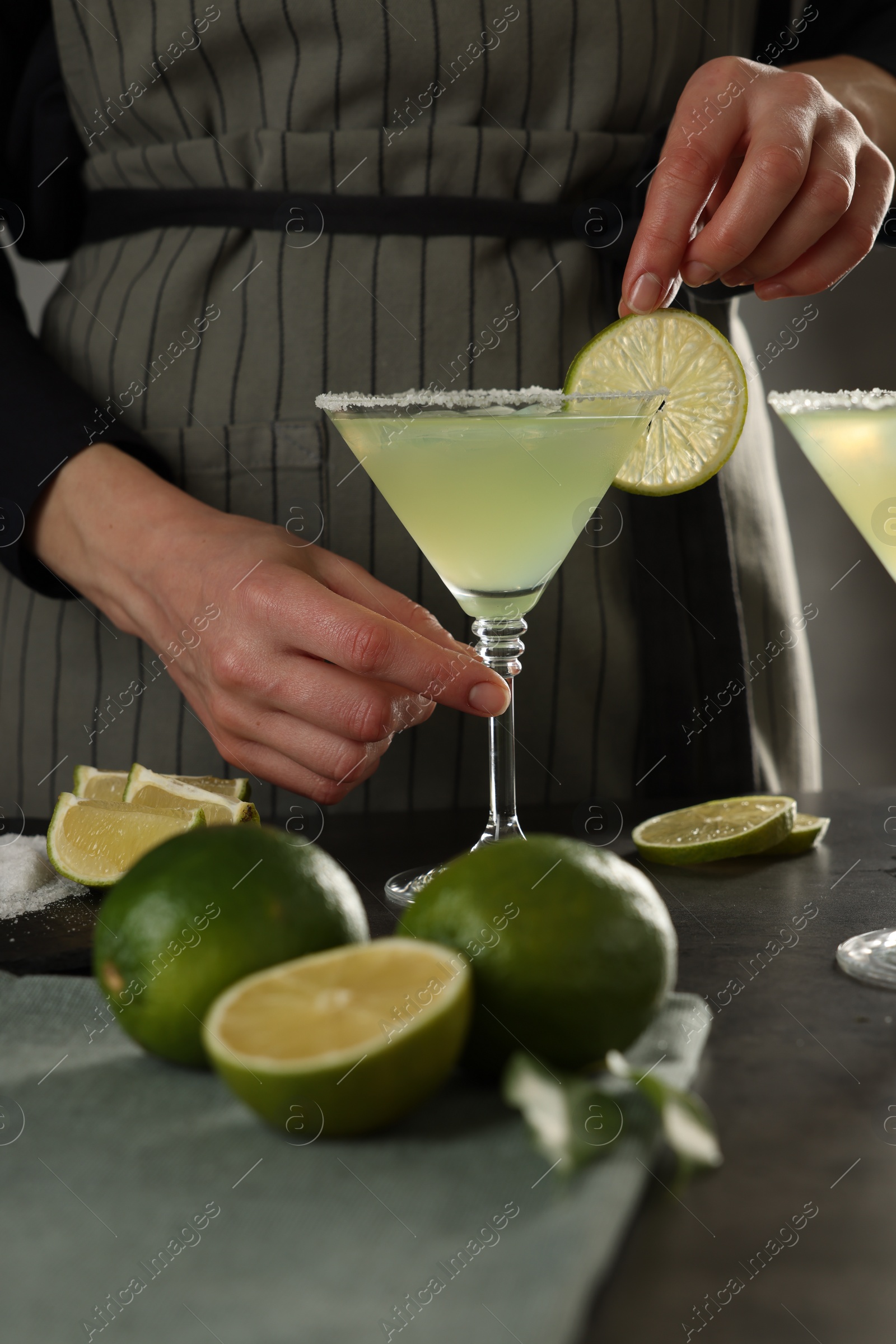 Photo of Woman making delicious Margarita cocktail at grey table, closeup