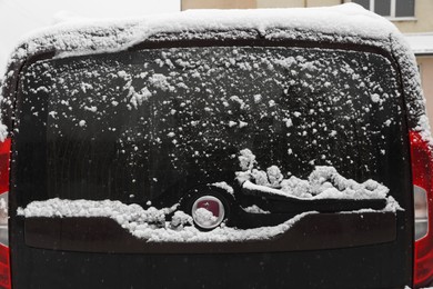 Photo of Car with rear windscreen wipers covered with snow outdoors on winter day