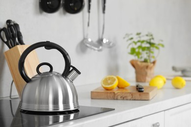 Photo of Stylish kettle with whistle on cooktop in kitchen. Space for text